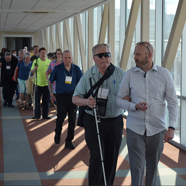 A large crowd of ACB Walk participants filter through a bright and sunny hallway.